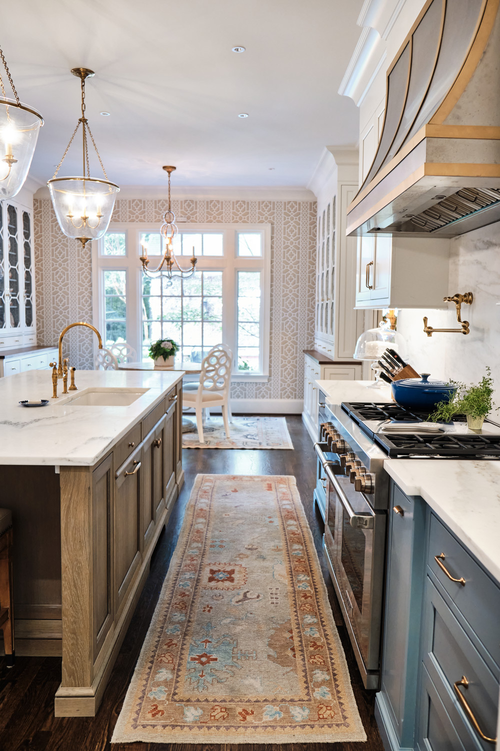 long view of dark wood floors with stainless steel and gold rimmed hood in kitchen