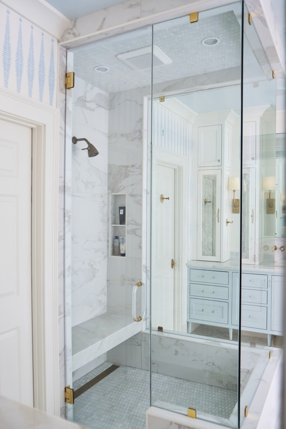 the large fully glass shower with marble floor is the centerpiece of the primary bathroom
