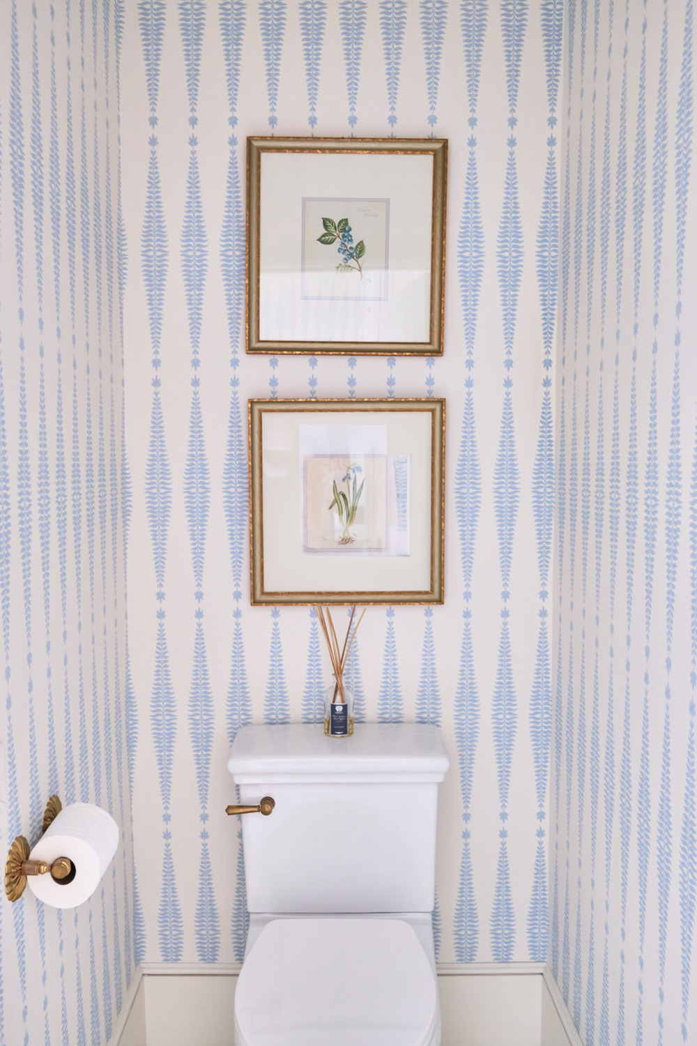 the toilet closet wallpaper matches the rest of the bathroom and the brass hardware touches complete the look