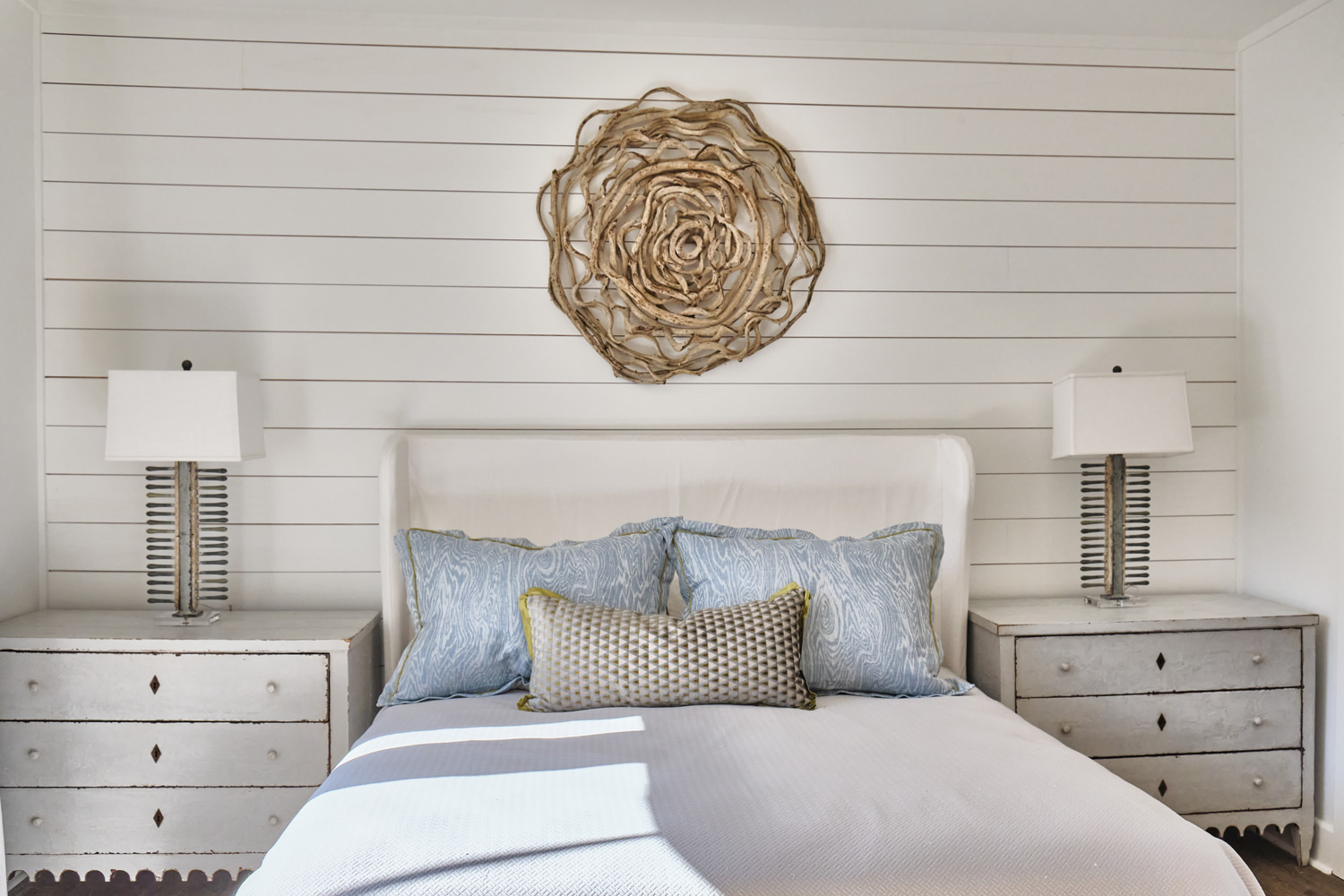 shiplap siding and natural decor over one of the beds
