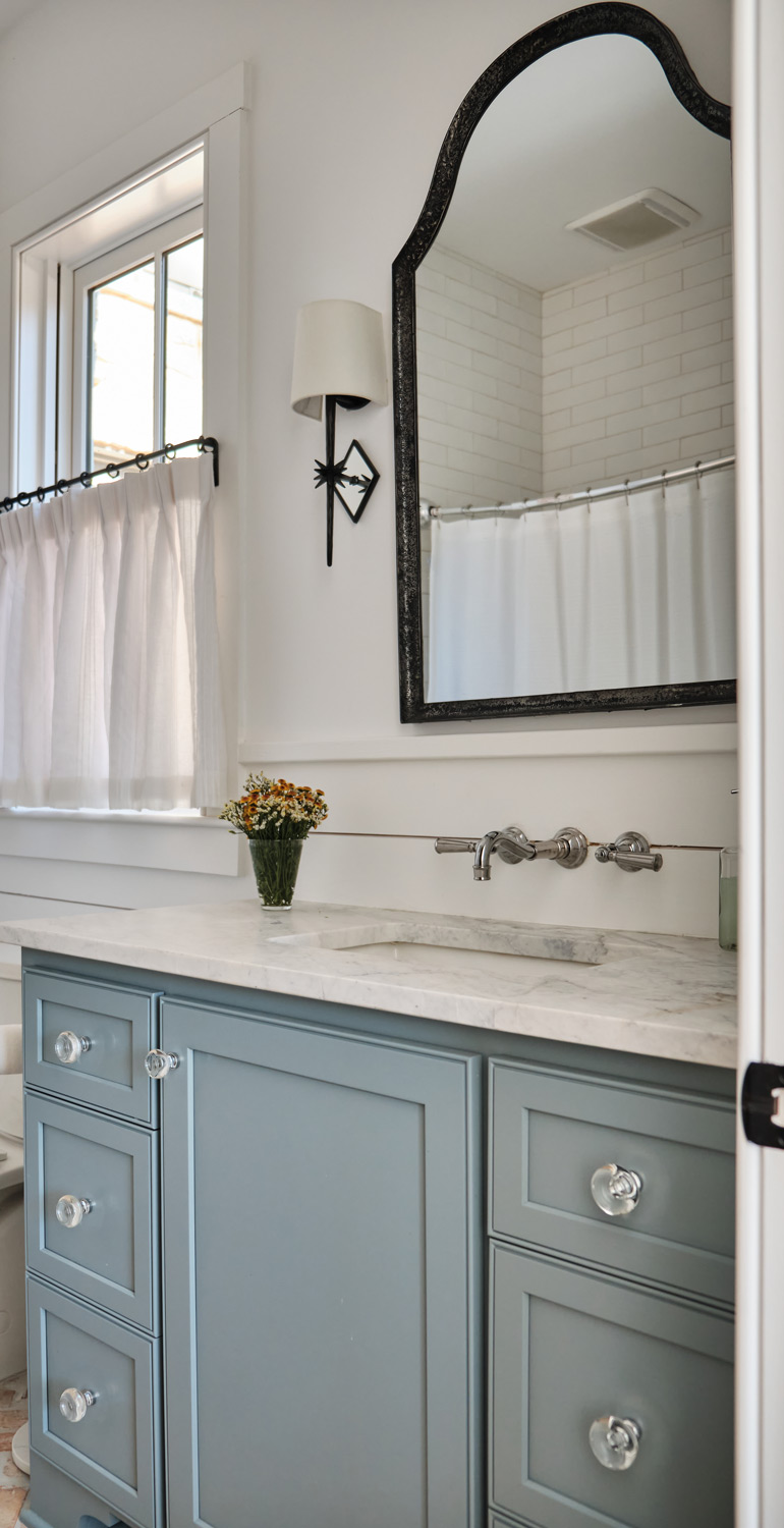 a gray blue vanity and iron sconces in a downstairs bedroom