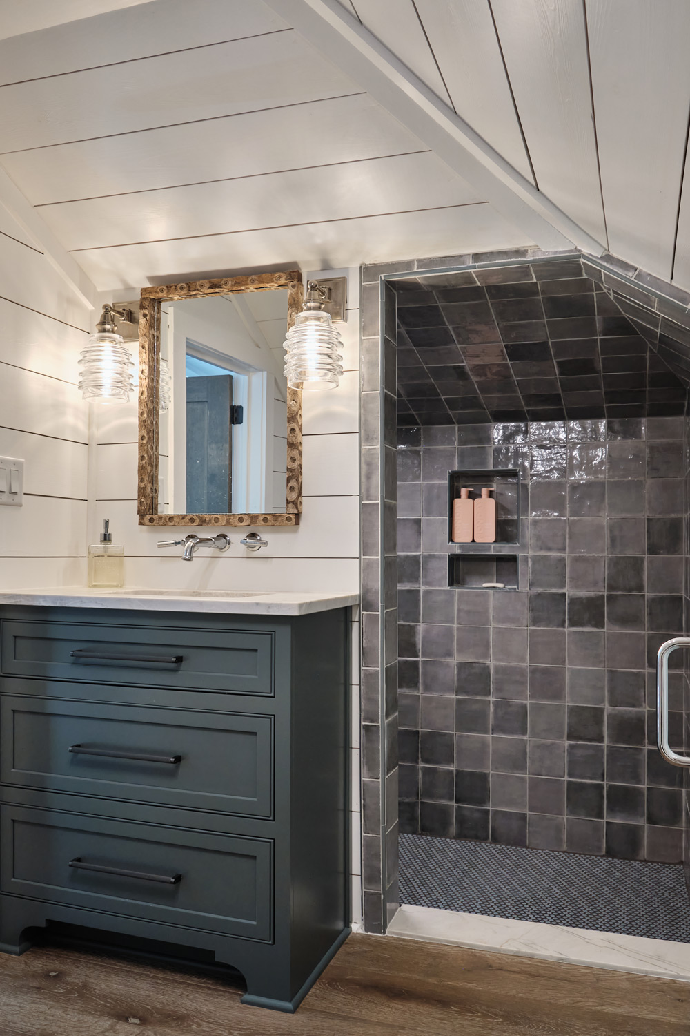 dark zellige tiles in a step down shower and a dark blue vanity contrast the white shiplap walls in the loft bathroom