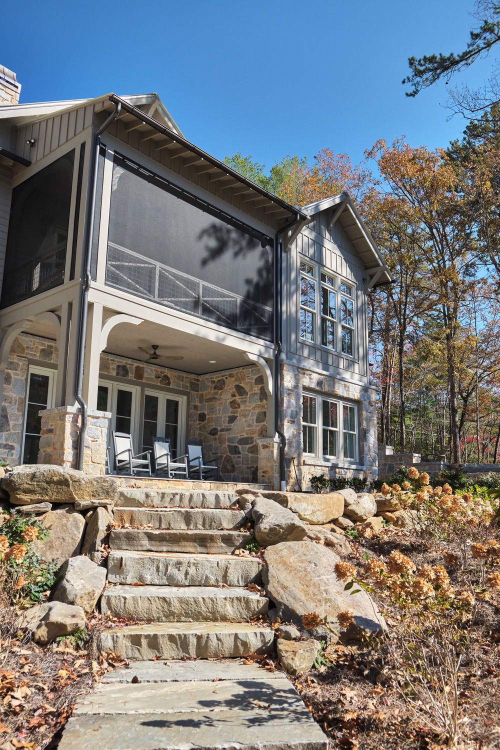 a view of the back of the house with screened in porch and stone walkway