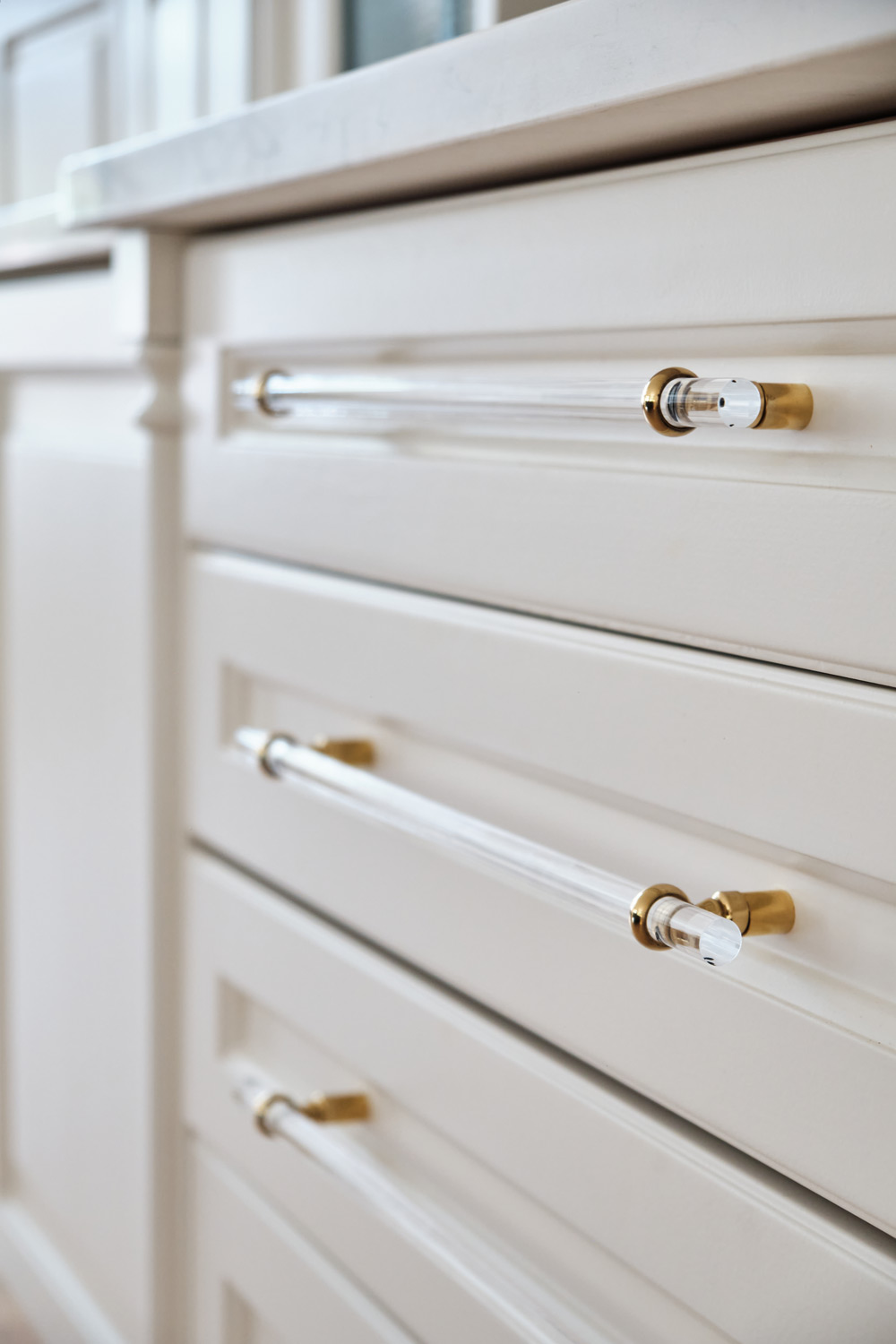 detail of the clear acrylic and gold pull handles on the custom cabinetry