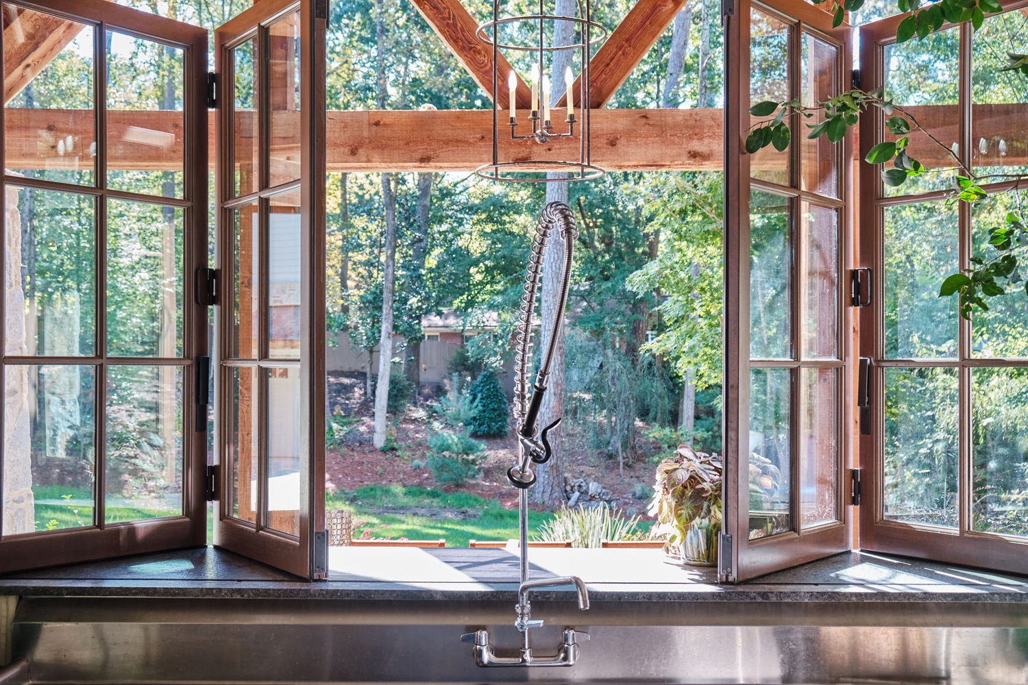 folding windows open up onto the outdoor dining area from the interior counter and sink