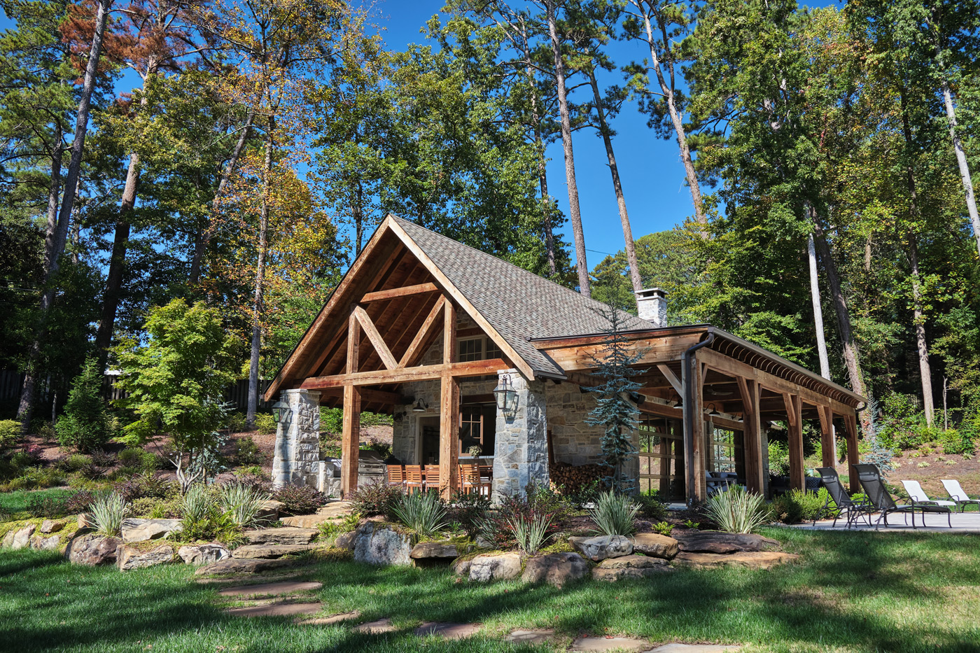 wide full view of pool house with stone and woodwork