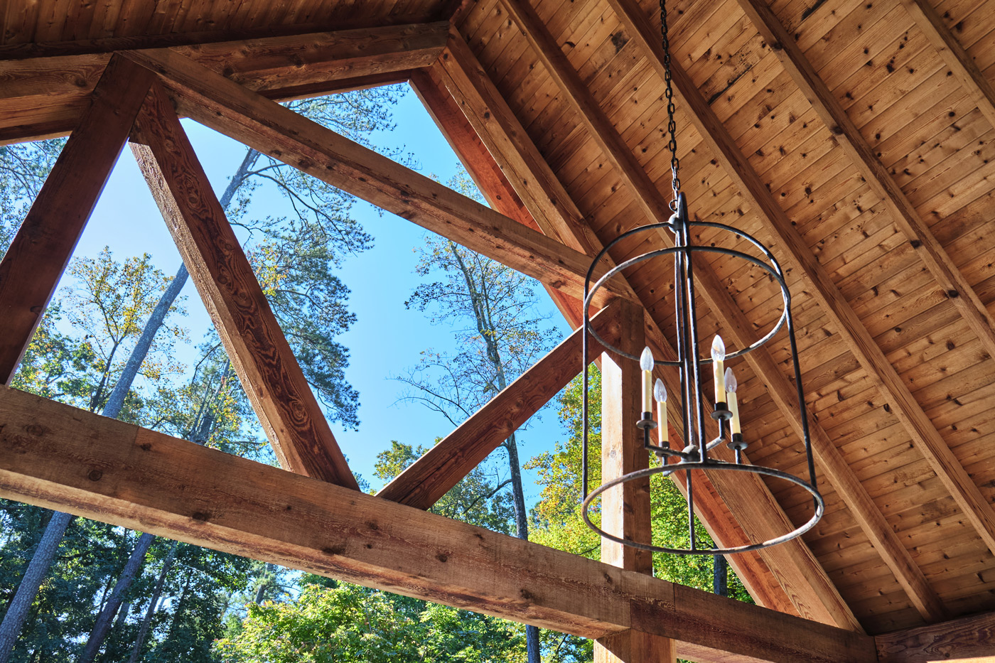 crisscrossed wood beams highlight a hanging iron lantern in the pool house's outdoor dining area